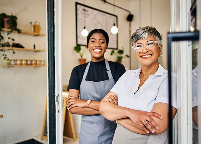Two people working at cafe standing in the doorway.